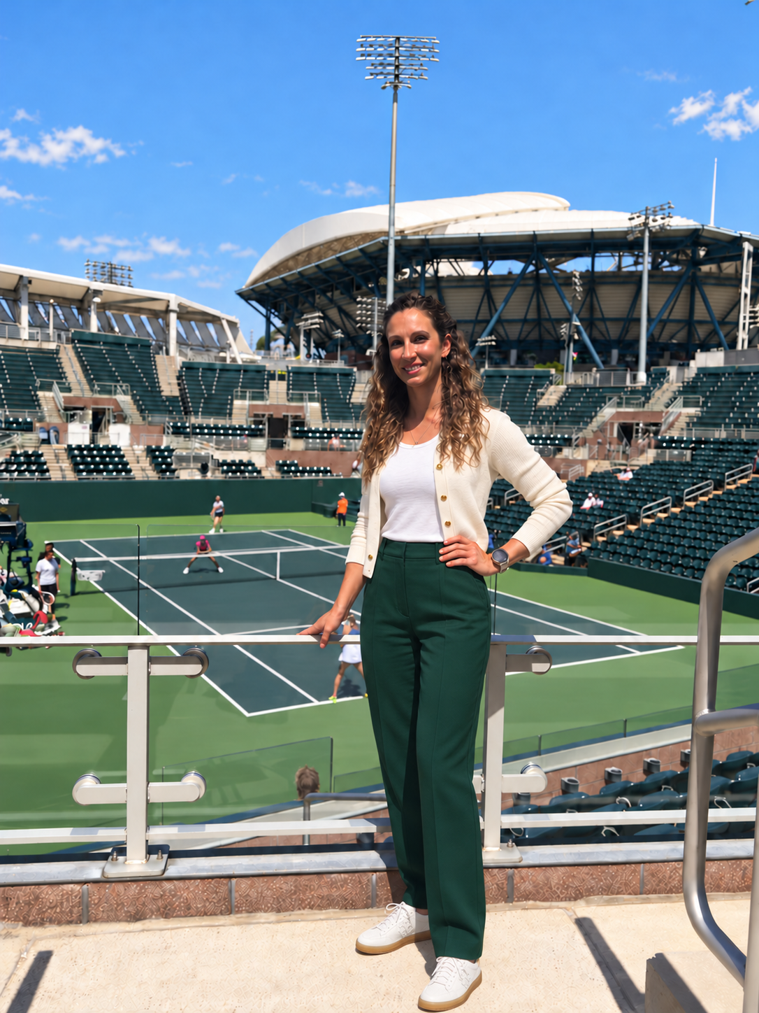 Erika Villalobos in an ivory cardigan and tailored forest-green trousers at a tennis venue
